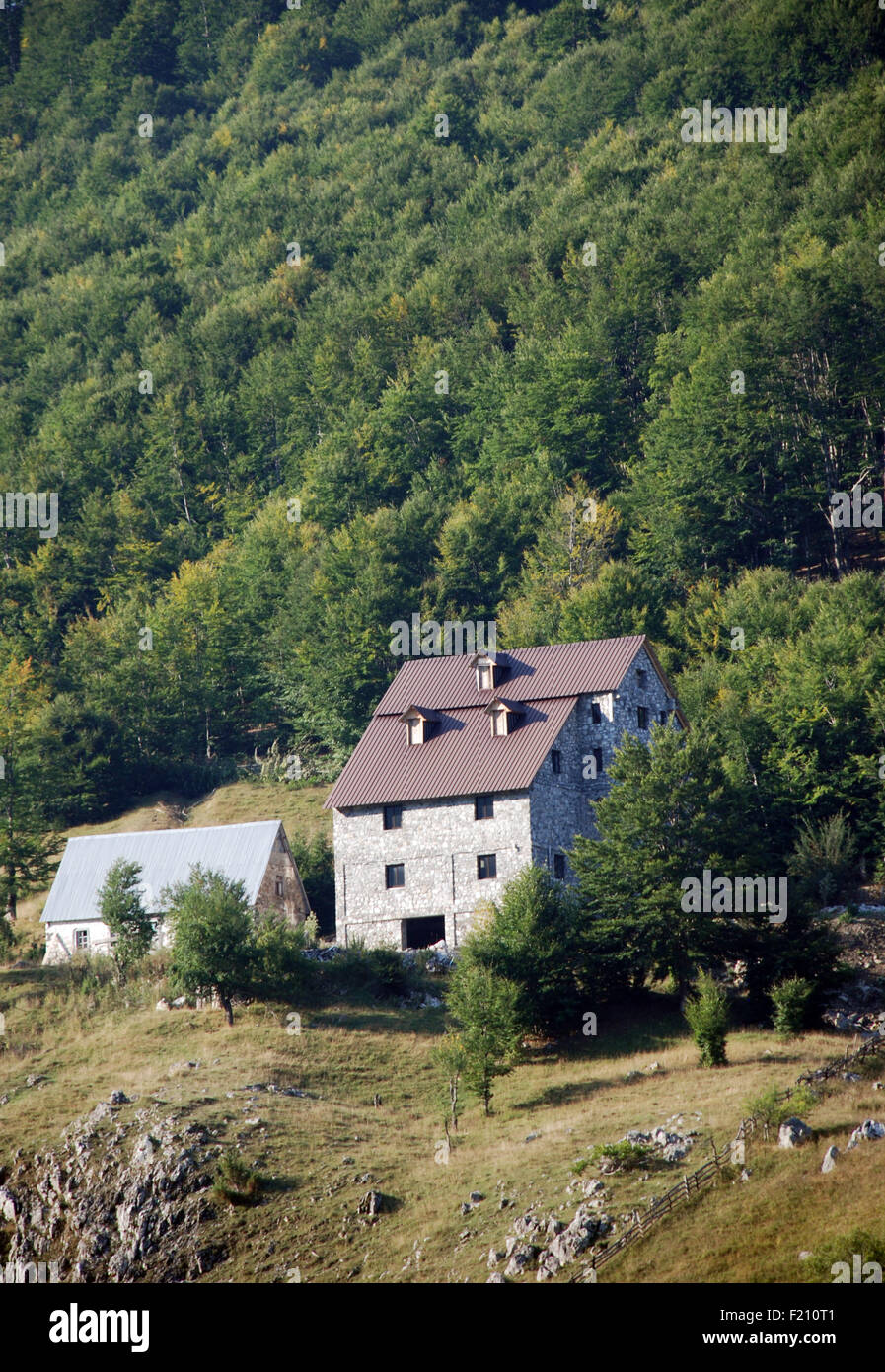 new building in the Albania village of Lepushe with a forested mountain slope behind it Stock Photo