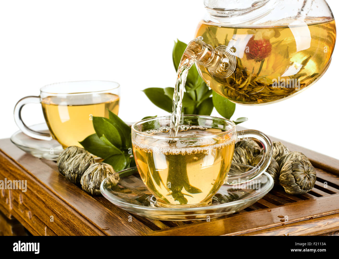 still life of the glass teapot flow green tea in cup on white