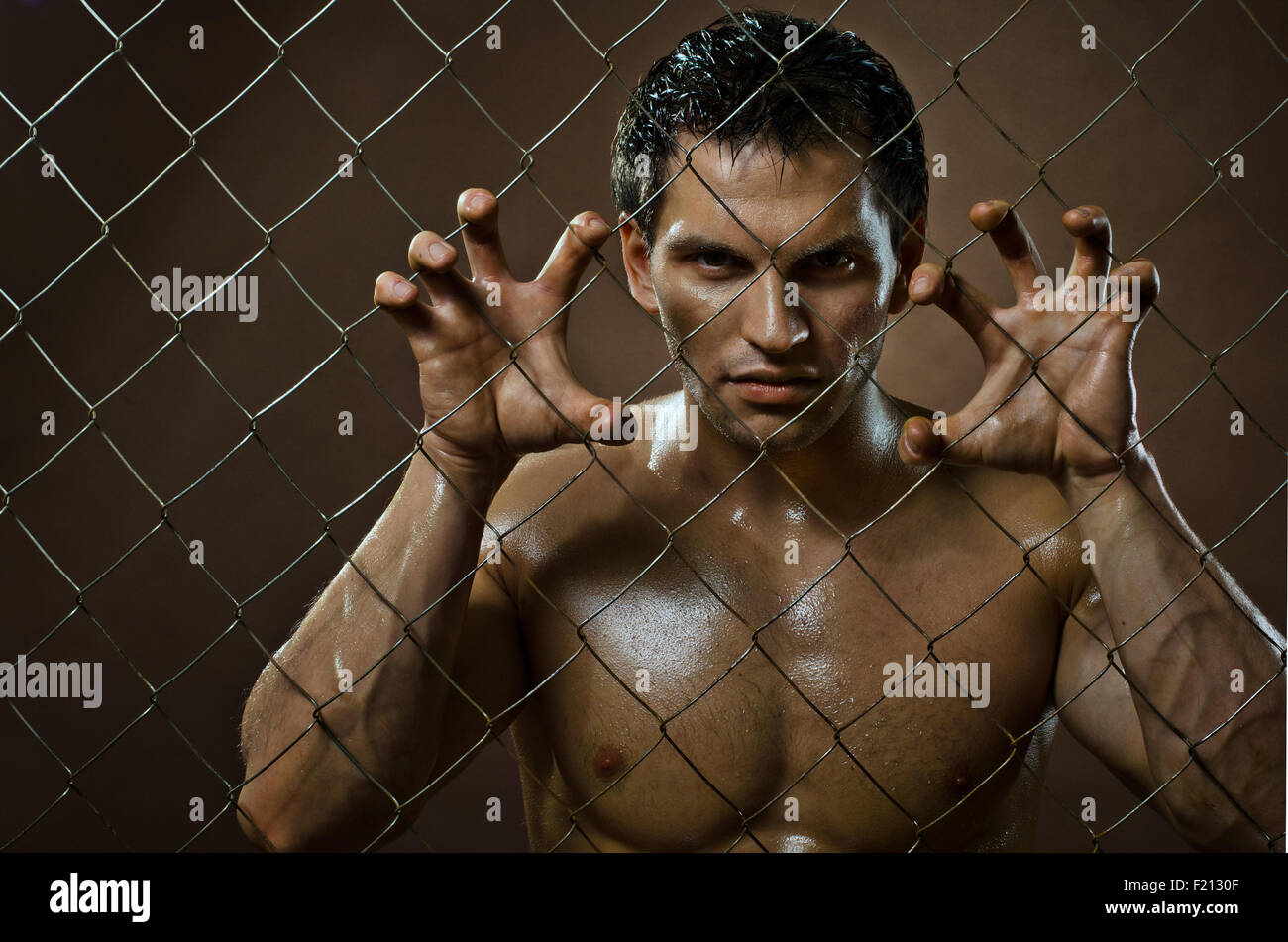 the very muscular handsome felon guy ,  out of netting   steel fence Stock Photo