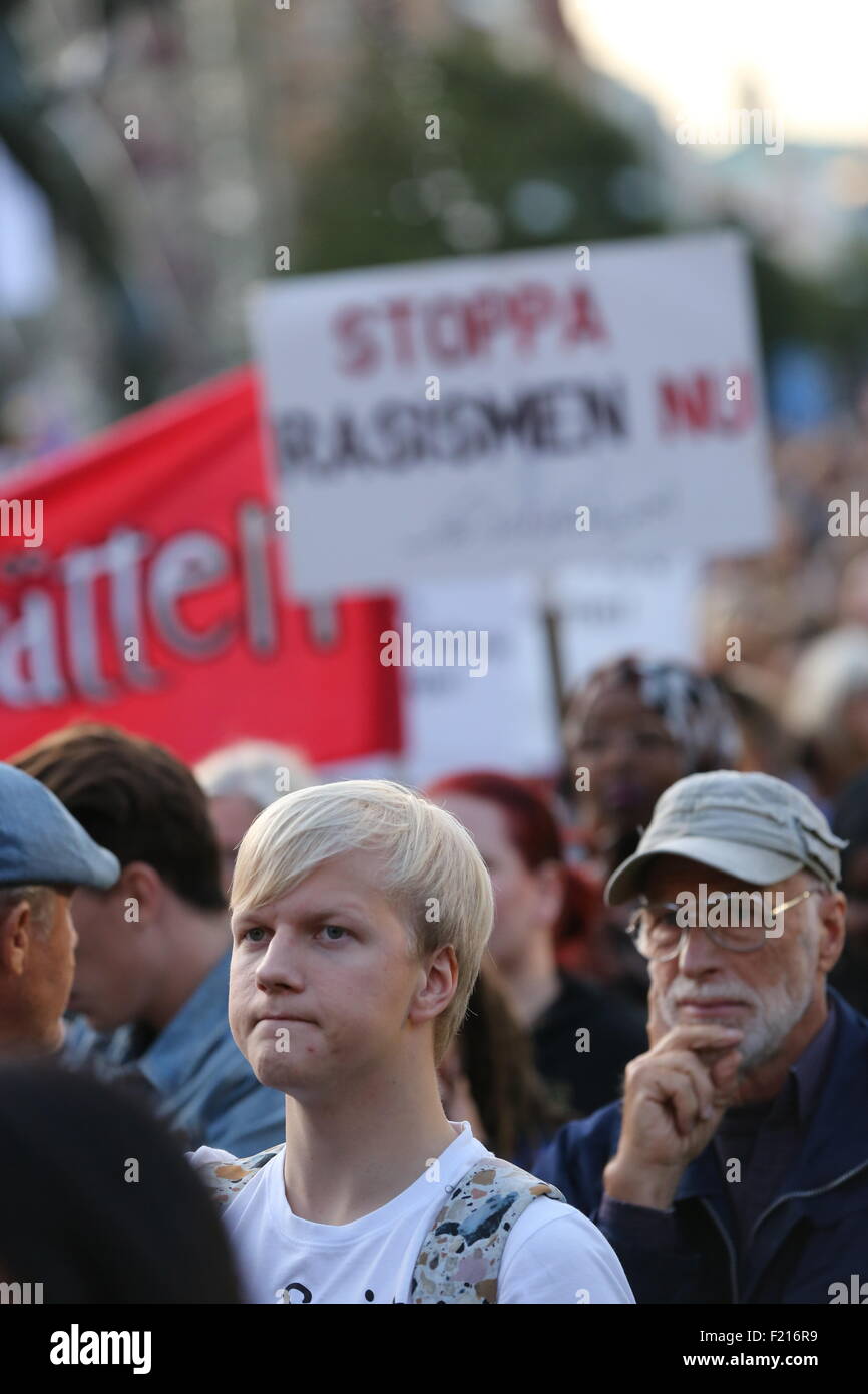 Serius man in the crowd during Refugees welcome rally in Gothenburg. With sign in the background saying Stop rascism now. Stock Photo