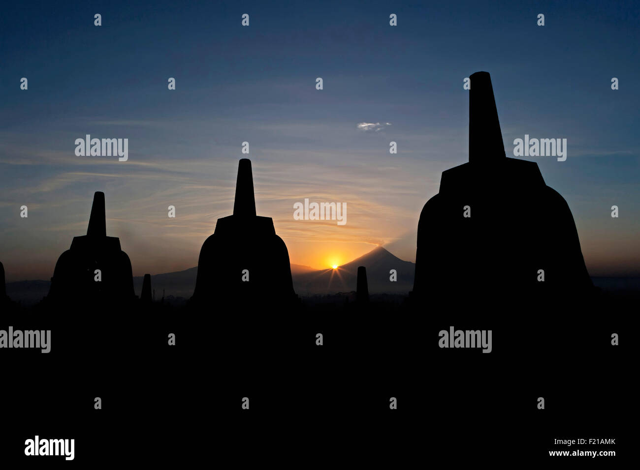 Indonesia, Java, Borobudur, Three stupas silhouetted against the sun ...