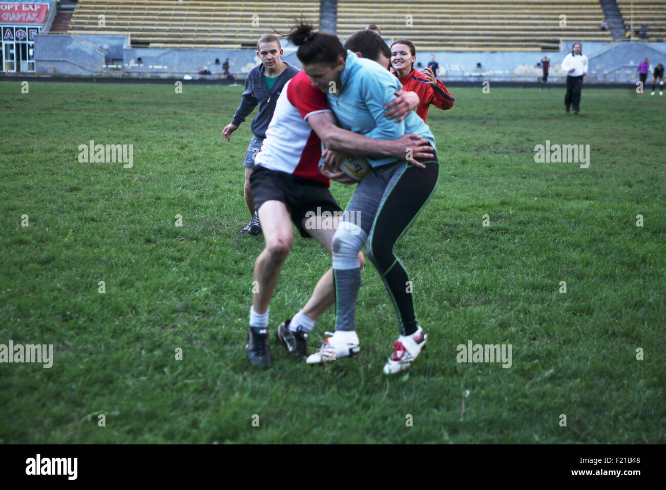 Kiev, Ukraine. 9th September, 2015. On 9 September Ukraine's Rugby squad (Female 18-) finishes training camp with playing male team from Eldorado school in Kiev on Spartak stad field. Pictured male player grabs young female opponent with a ball to stop her while her team mates hurry to help her Stock Photo