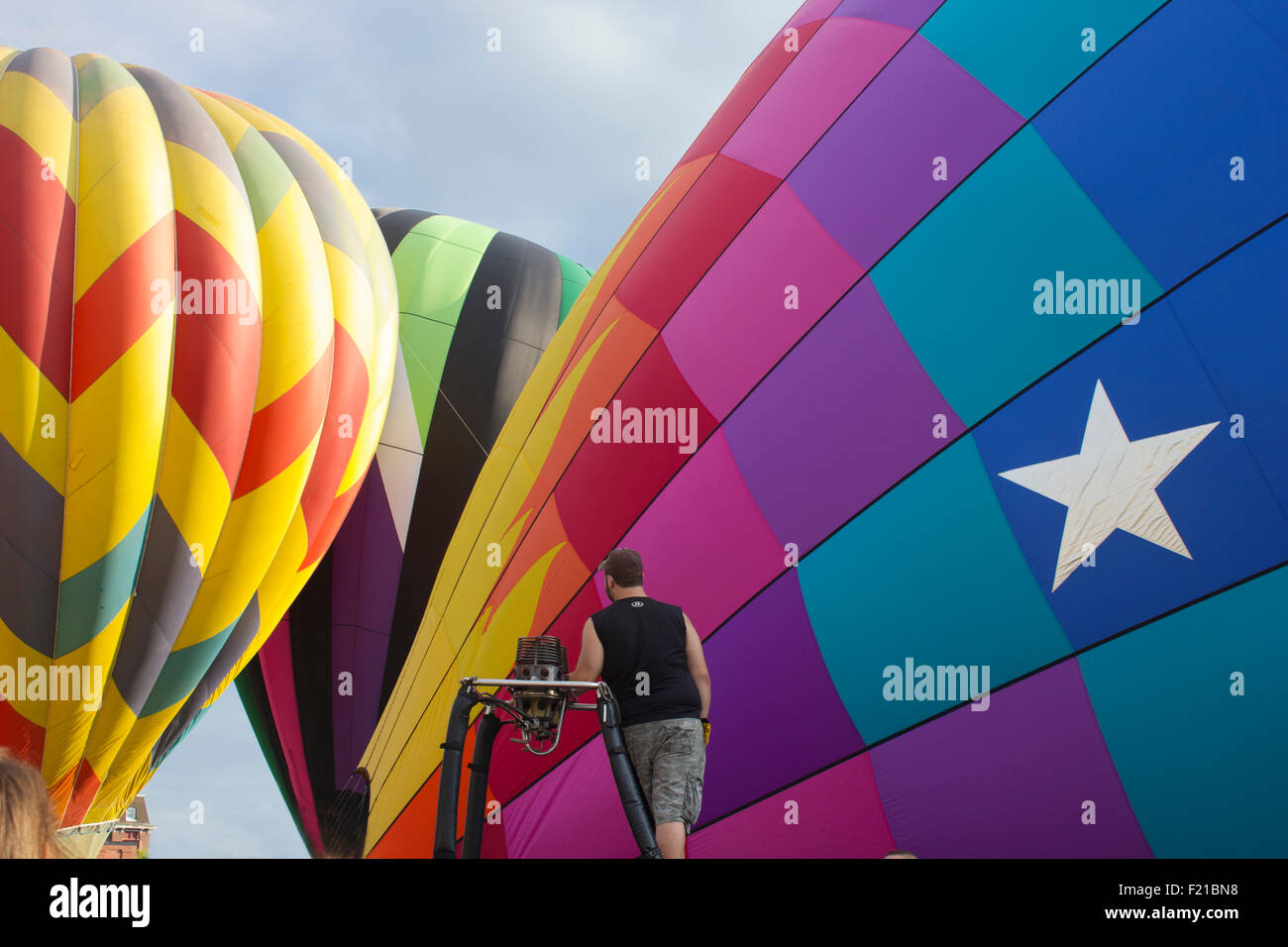 Three hot air balloons preparing to launch while one of the pilots