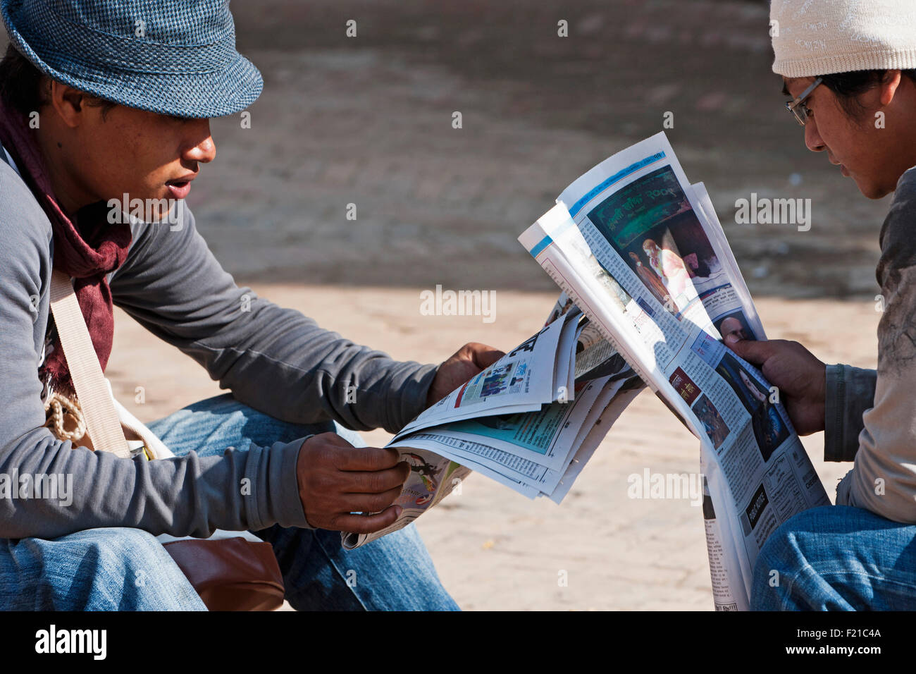 Nepal Kathmandu Two Teenage Nepali Males Reading Newspapers Opposite Each Other In The Shadow 