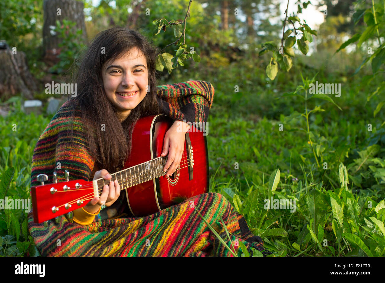 Young girl with an acoustic guitar sitting in the grass Stock Photo - Alamy