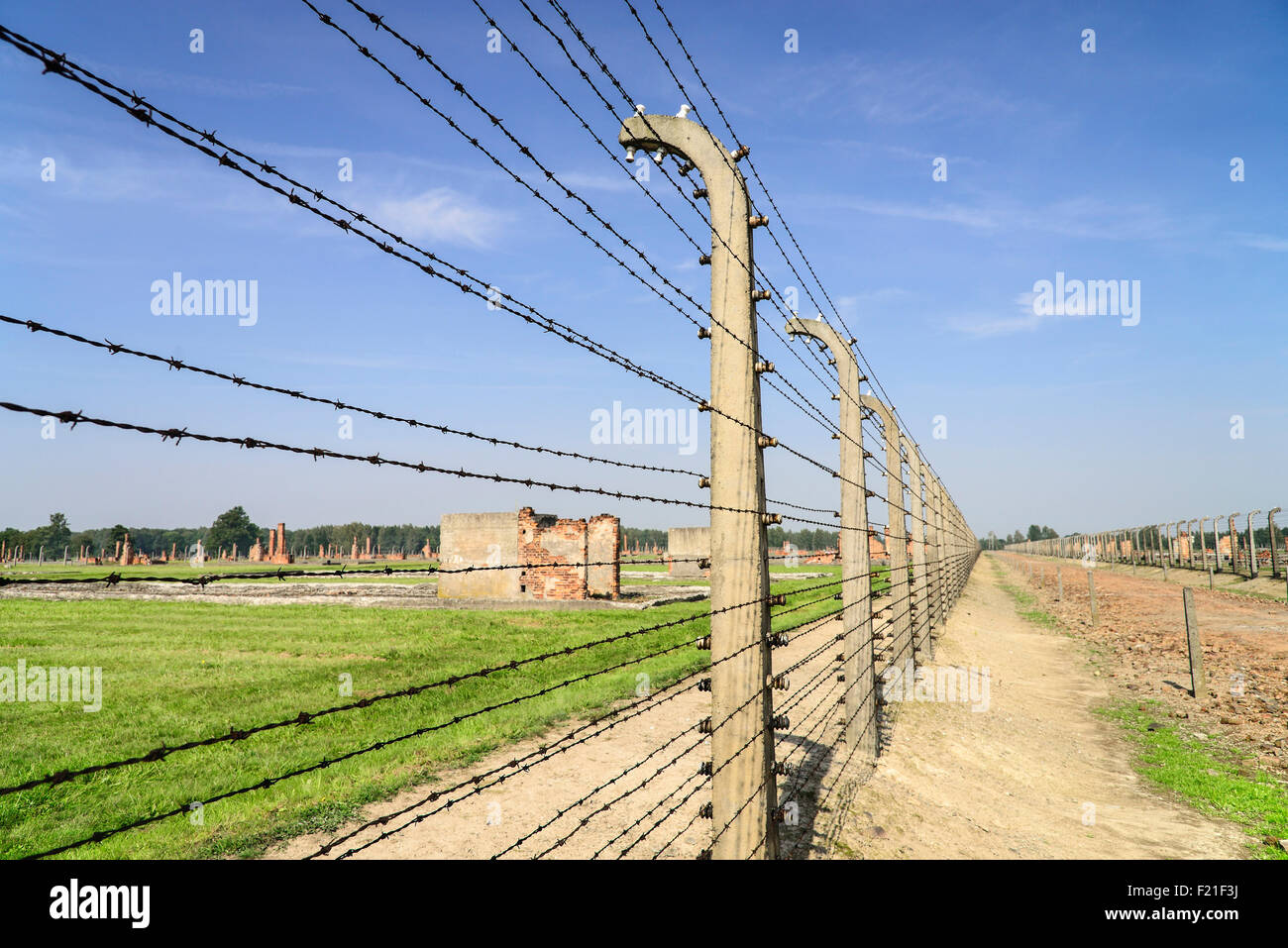 Poland Auschwitz-Birkenau State Museum Birkenau Concentration Camp Ruins of former accommodation blocks surrounded by barbed Stock Photo