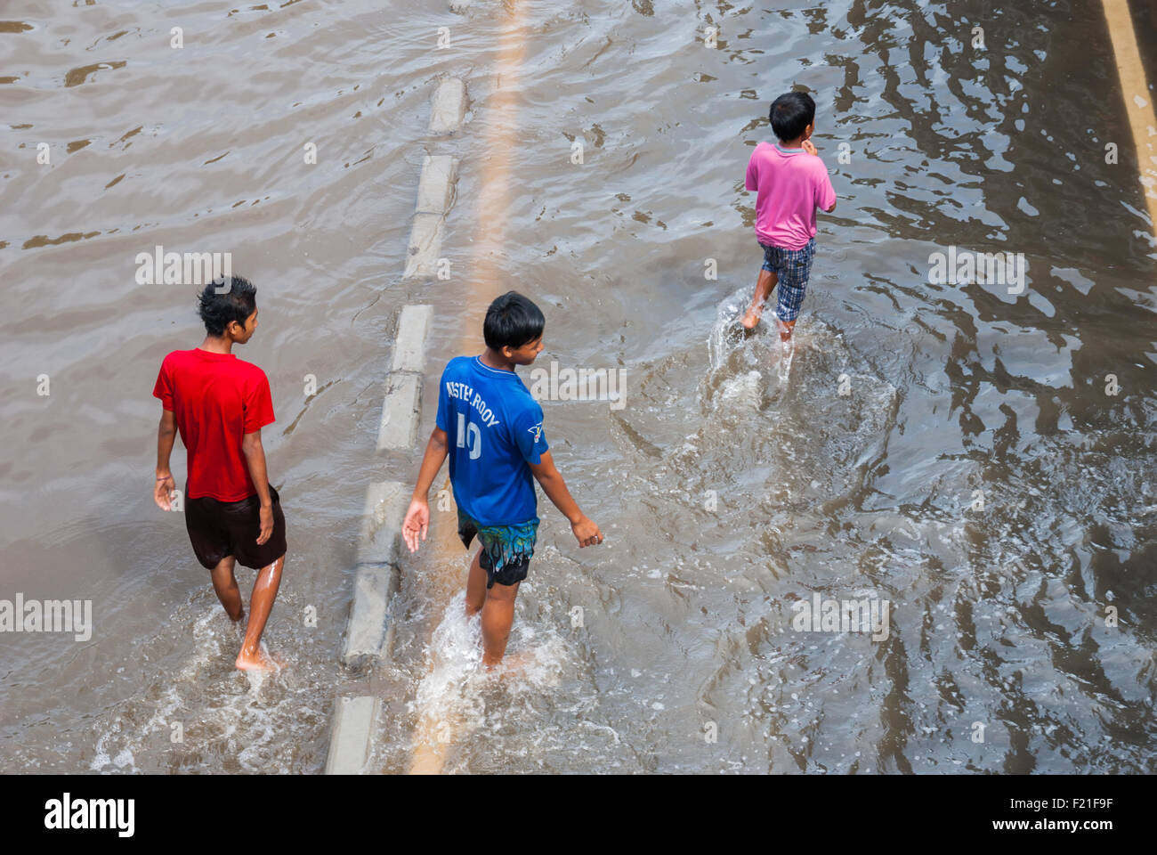 Children walking on flooded street. Stock Photo