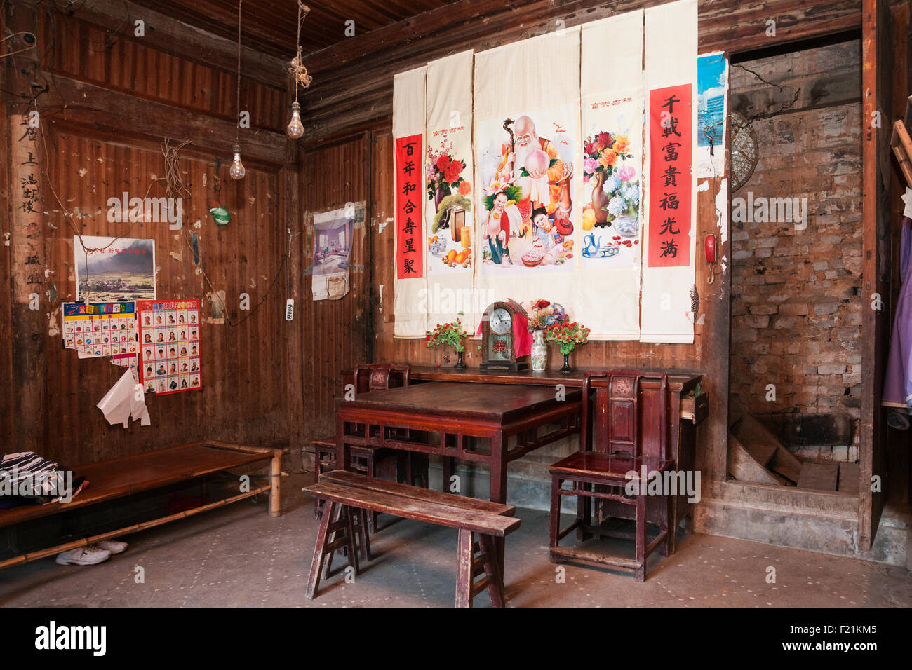 Interior of a living room with table and chairs and Chinese script and illustrative decorations in Shichuon village, China Stock Photo