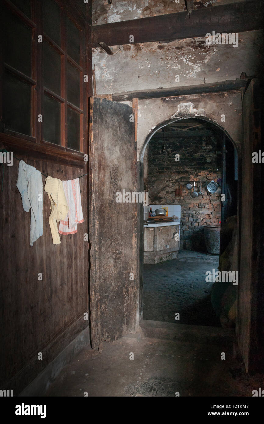Dim interior showing a hallway leading to the kitchen in a home without electricity in Shichuon