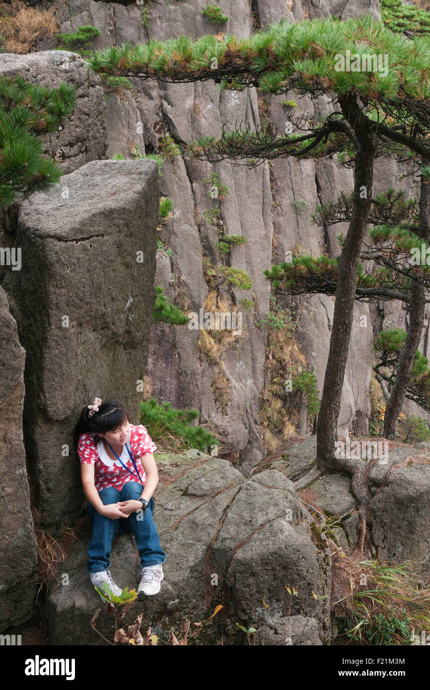 Girl in pink rabbit top sits on a rock along  Brightness Peak trail, Yellow Mountain, Huangshan, Anhui province, China, Asia Stock Photo