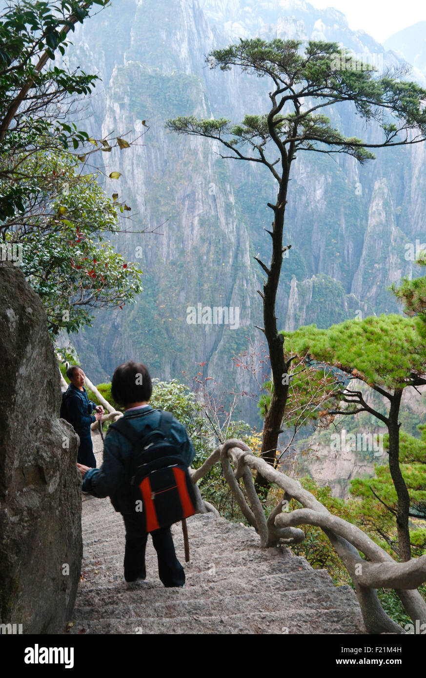 Mature Asian couple descend concrete steps built into rock face on the Xihai Grand Canyon trail, Yellow Mountain, Huangshan Stock Photo