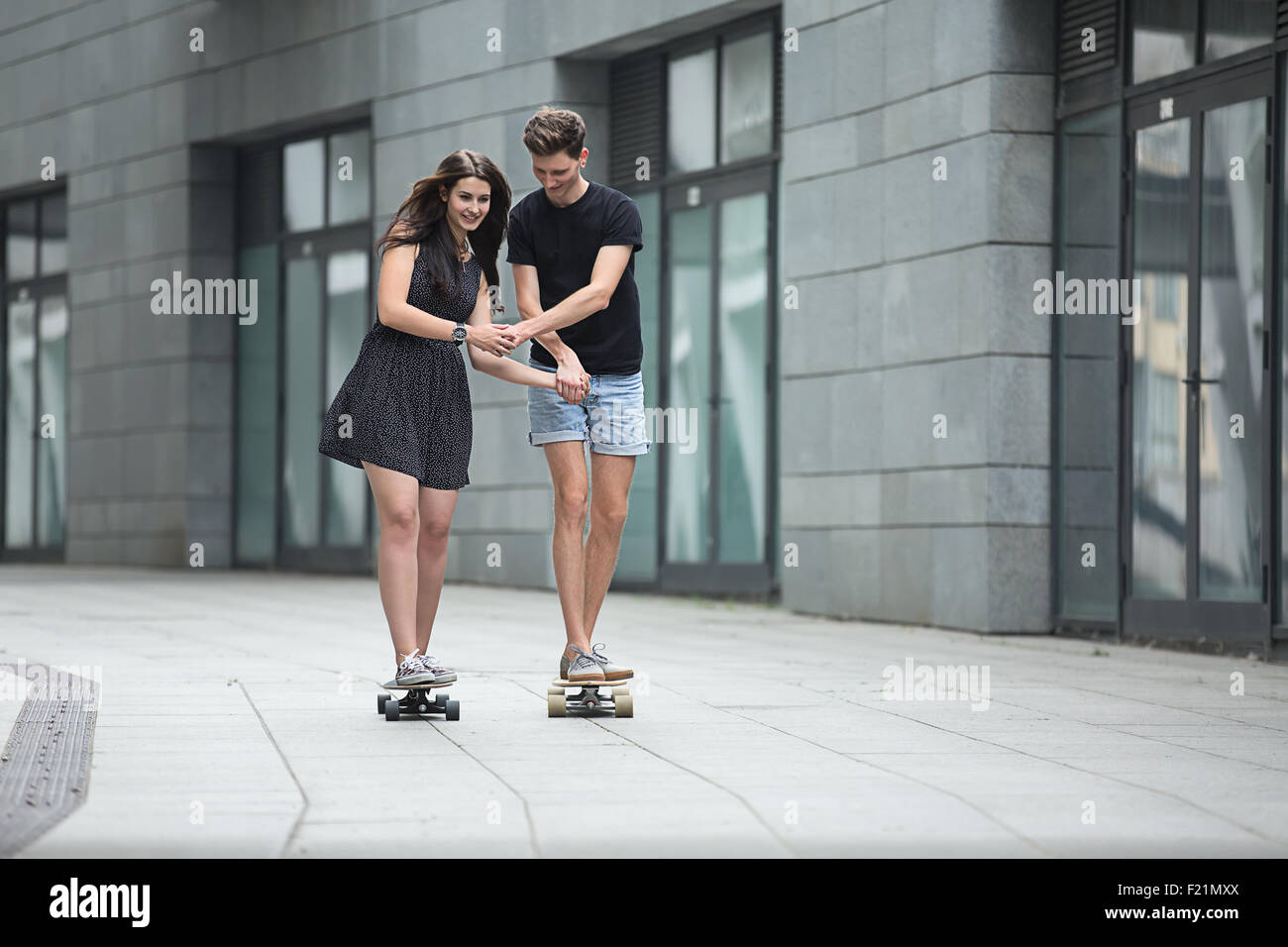 Young pair in love of stylish teenagers ride longboards Stock Photo