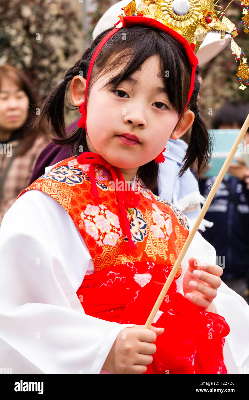 Genji Tada shrine festival. Parade of children dressed in Heian period costume. Young girl, 6-8 year old, with gold crown, white robe and red jacket. Stock Photo