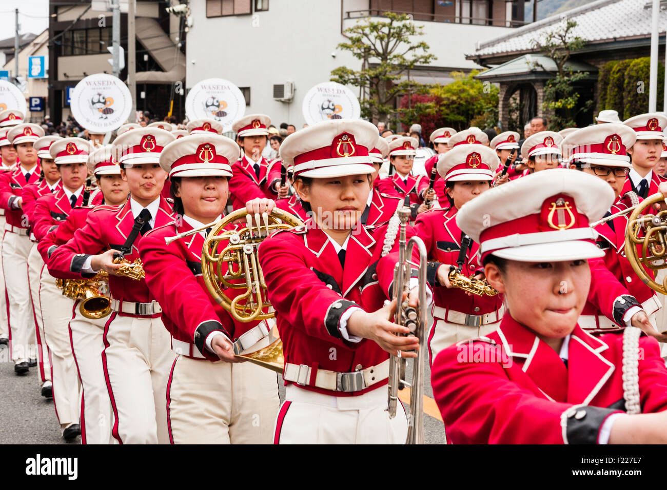 Genji Festival parade in Japan. Women's brass band marching at head of parade. Band members dressed in white and pink military style uniforms. Stock Photo