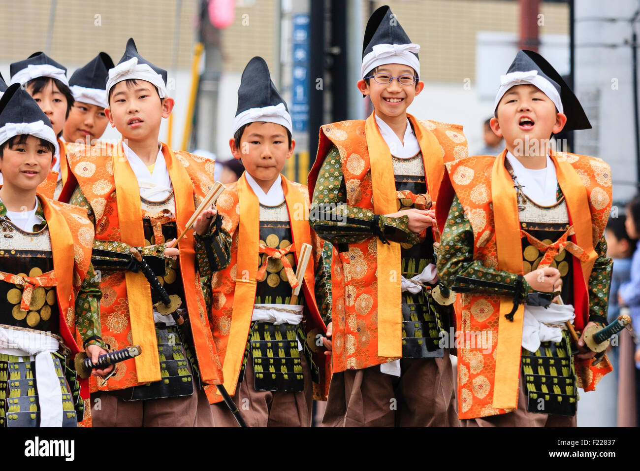Genji Festival parade in Japan.Young children, boys, 8-10 year old, dressed as Shimobe soldiers from the heian era. Green armour and orange robe. Stock Photo