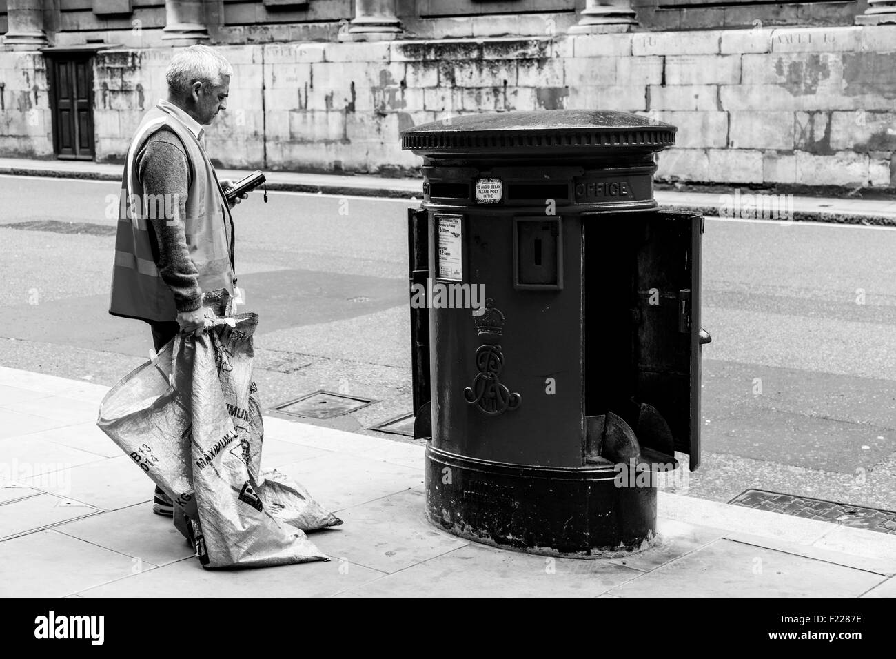 A Royal Mail Worker Collects The Mail From A Post Box In Central London, England Stock Photo