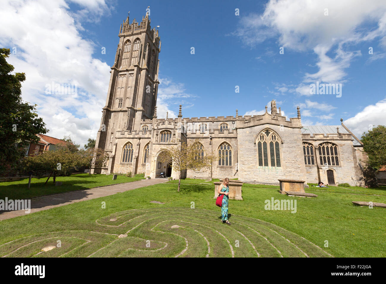 A woman walking around the Tercentennial Labyrinth in front of the Church of St John the Baptist, Glastonbury town, Somerset UK Stock Photo