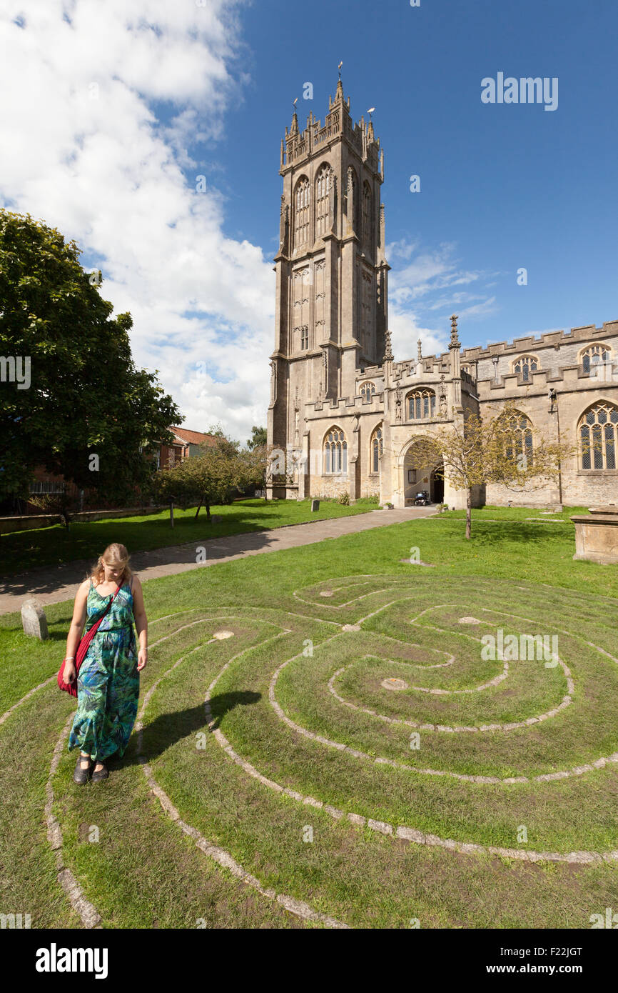 A woman walking around the Tercentennial Labyrinth in front of the Church of St John the Baptist, Glastonbury town, Somerset UK Stock Photo