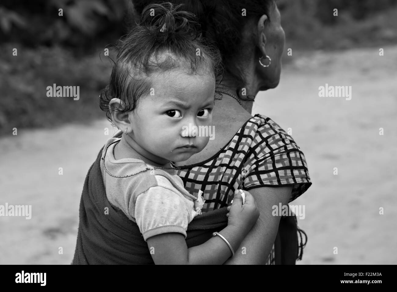 candid portrait of a cute Nepalese baby riding on her grandmother's back Stock Photo