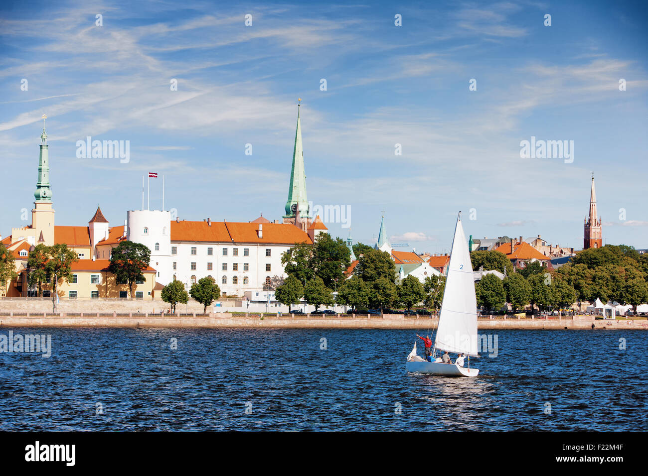 The boat on the river from the castle President of Latvia on the waterfront and city skyline Riga churches with spiers Stock Photo