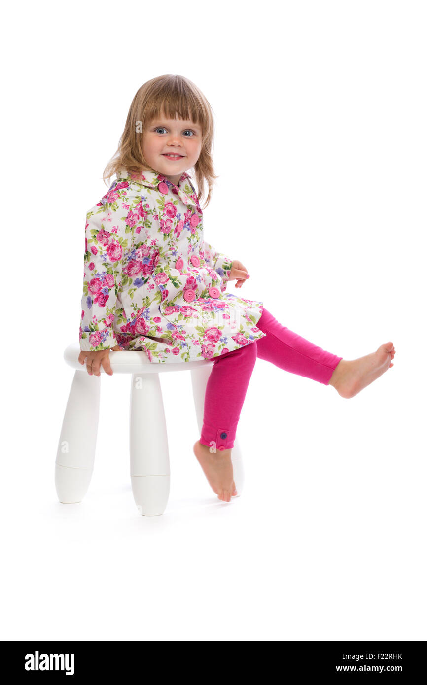 Little smiling girl sitting on a chair in the studio, isolate on white ...