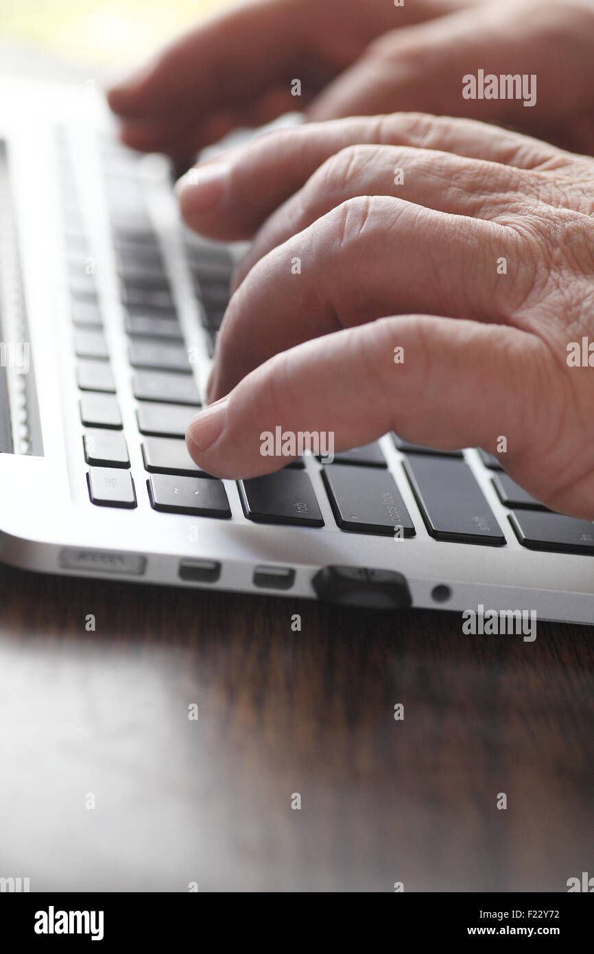 Senior man hands at a laptop keyboard Stock Photo