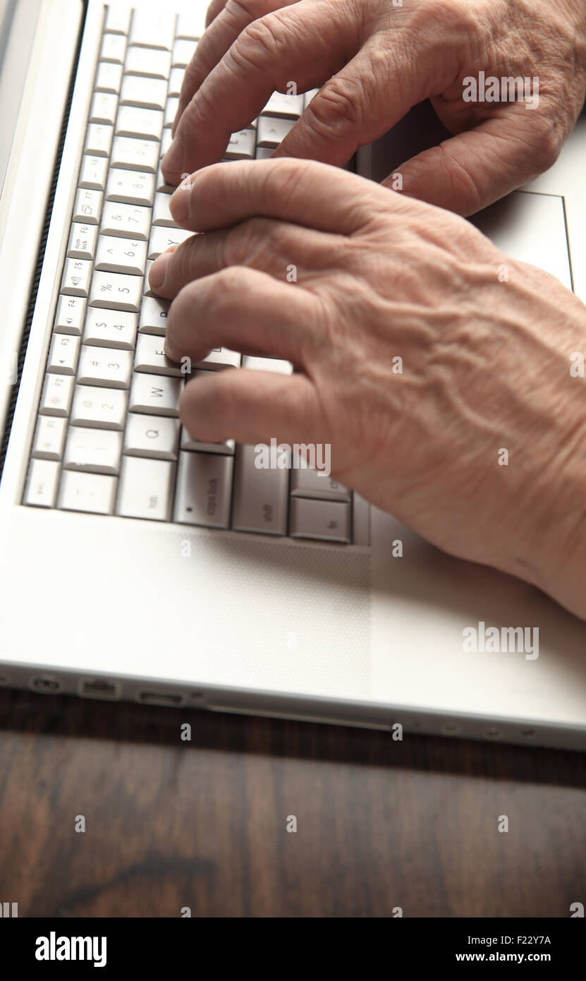 Older man's hands on his laptop keyboard with copy space Stock Photo