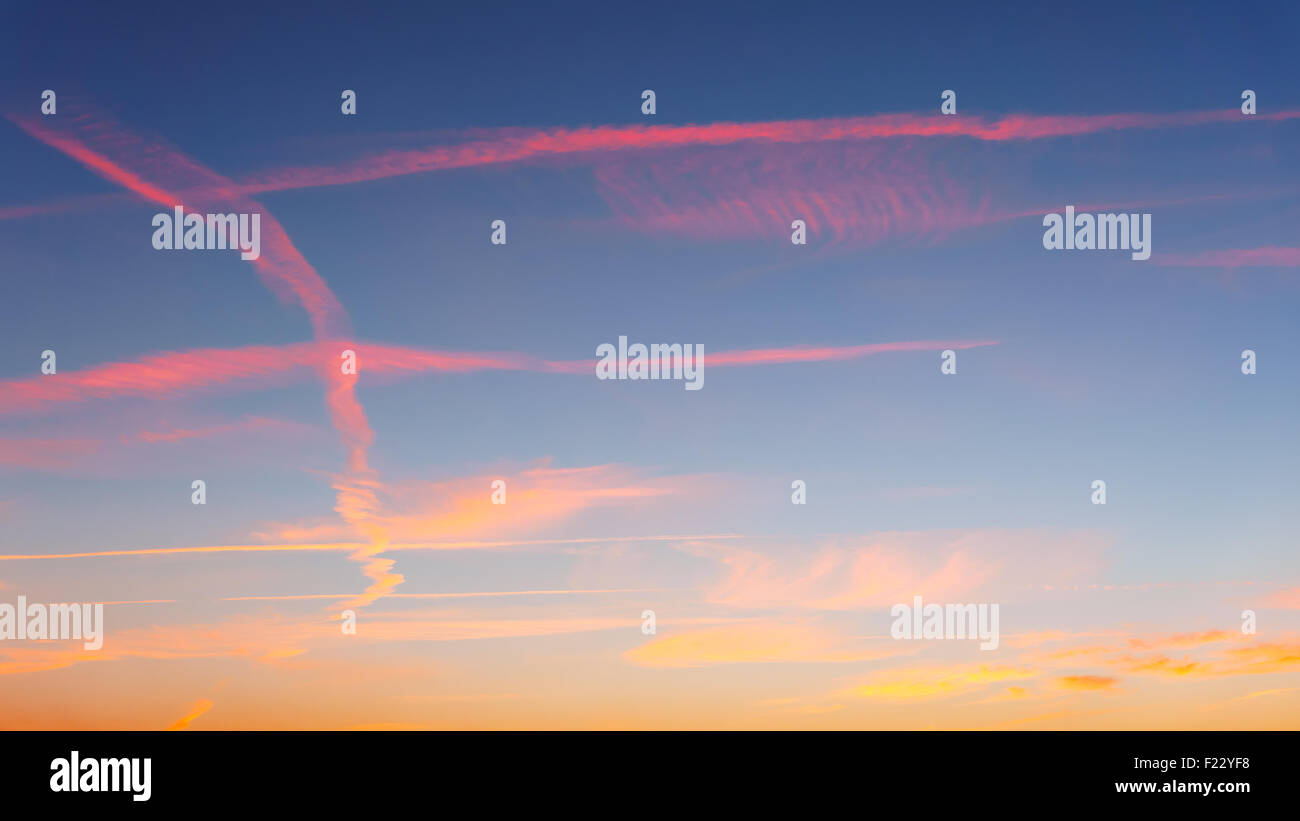 cloudscape with airplane trails at the sunset Stock Photo