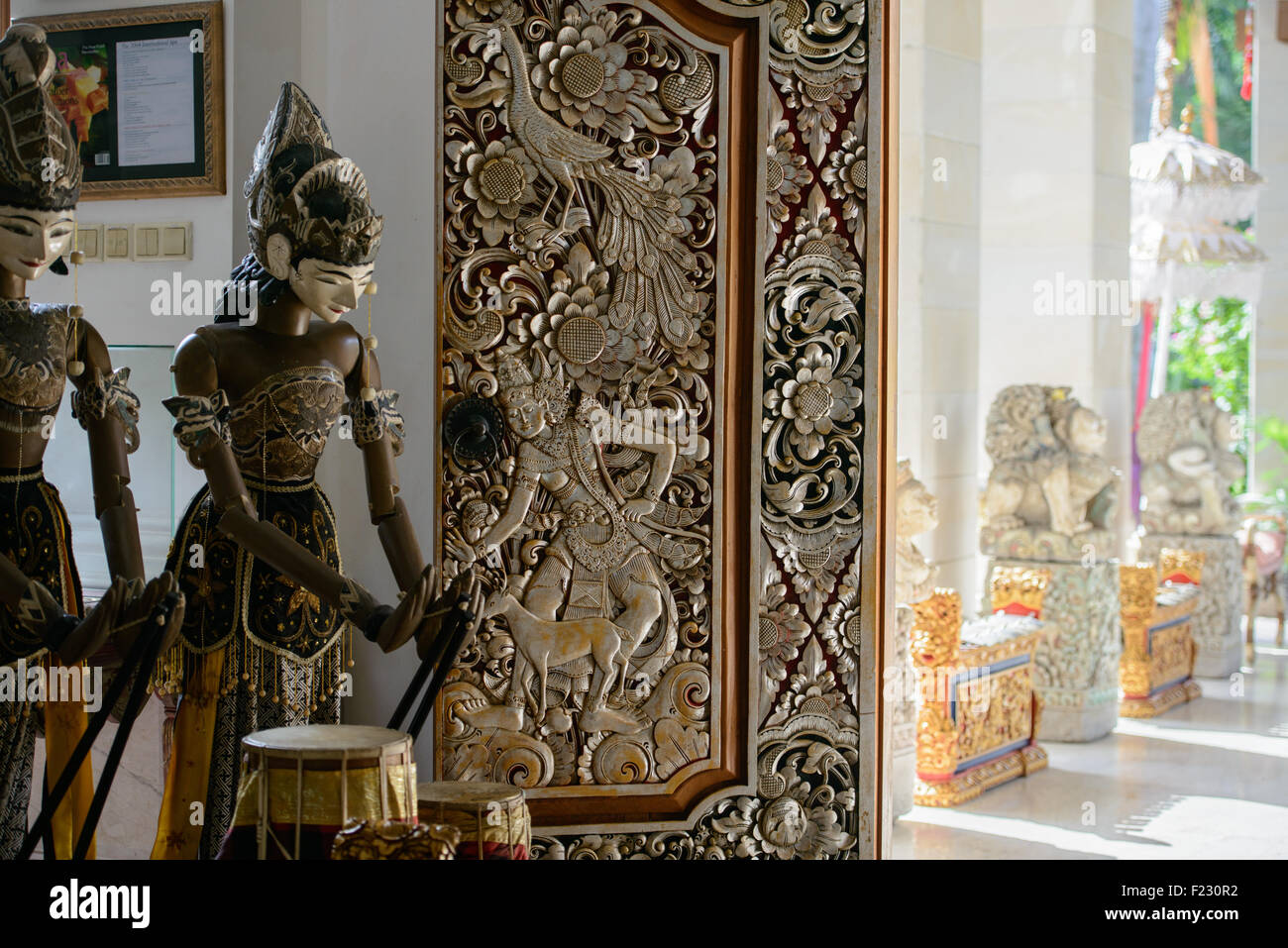 Balinese puppets beside a carved wooden door form an attractive triptych seen in this Ubud hotel Stock Photo