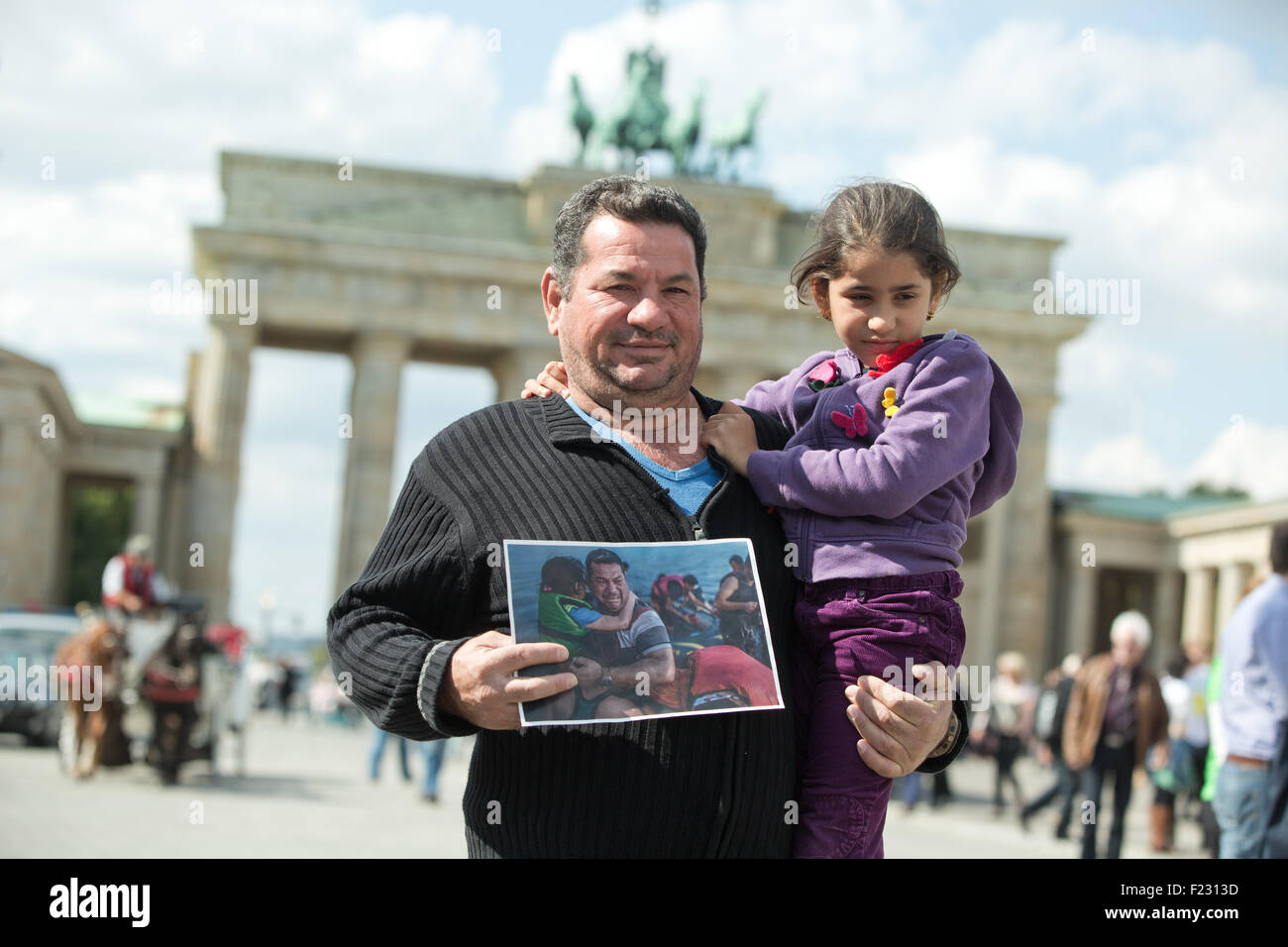 Berlin, Germany. 10th Sep, 2015. Iraqi refugee Laith Majid Al-Amirij and his 7-year-old daughter Noor pose with a photo showing them during their crossing on the Greek island of Kos, in front of the Brandenburg gate in Berlin, Germany, 10 September 2015. The photo was seen around the world. First published in mid-August in the New York Times, it was shared thousands of times on social media. The family are now being housed in Berlin. PHOTO: JOERG CARSTENSEN/DPA/Alamy Live News Stock Photo