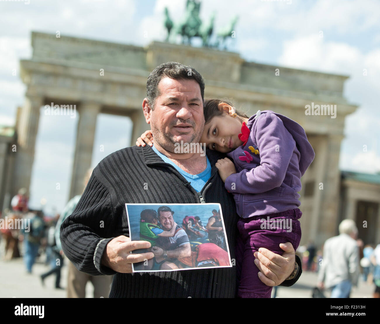 Berlin, Germany. 10th Sep, 2015. Iraqi refugee Laith Majid Al-Amirij and his 7-year-old daughter Noor pose with a photo showing them during their crossing on the Greek island of Kos, in front of the BRandenburg gate in Berlin, Germany, 10 September 2015. The photo was seen around the world. First published in mid-August in the New York Times, it was shared thousands of times on social media. The family are now being housed in Berlin. PHOTO: JOERG CARSTENSEN/DPA/Alamy Live News Stock Photo