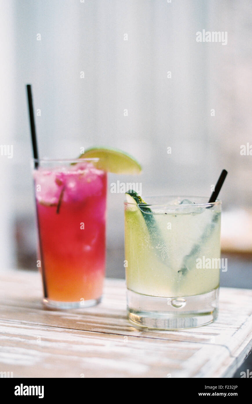 Two glasses of chilled drinks, with straws and garnishes. Lemonade and iced tea. Stock Photo