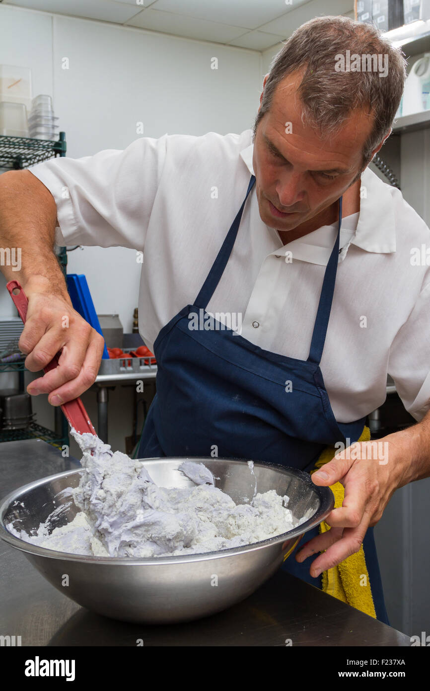 professional chef folding different ingredients into a batter in a