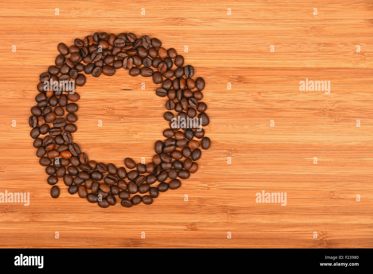 Circle shaped coffee beans of Roasted Arabica espresso beans frame over wooden bamboo board background Stock Photo