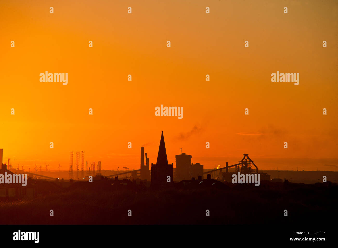 sun sets over Redcar SSI Steelworks industry silouetted against an orange glow Stock Photo