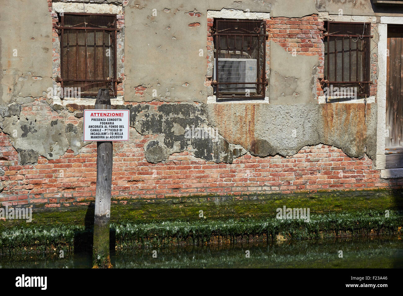 Sign in Italian warning boats of danger of running aground in the canal because of a sewer Chioggia Venetian Lagoon Veneto Italy Stock Photo