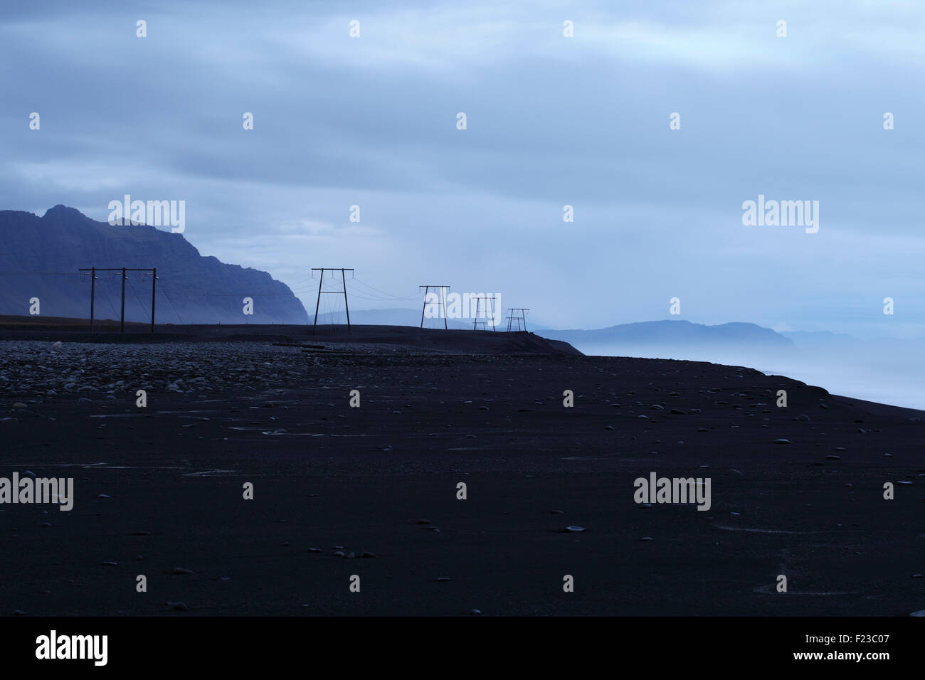 Pylons carry wires along the southeast coast of Iceland Stock Photo