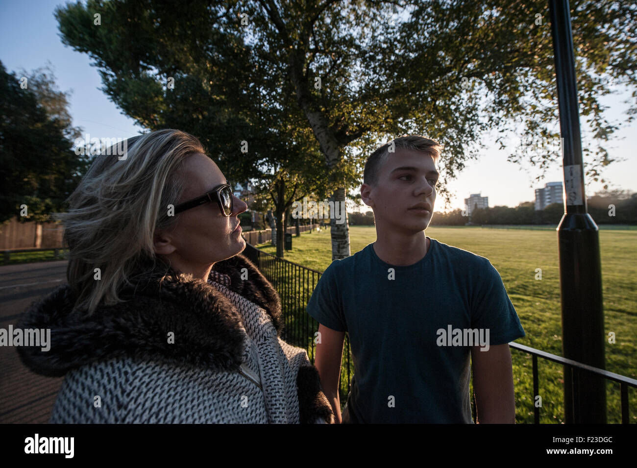 A glamorous mother and her son on a walk in a london park at dusk Stock Photo