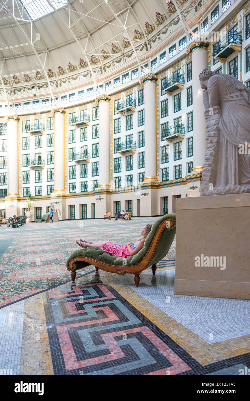 Velvet Atrium Caucasian girl wearing a pink dress reclines on a velvet chaise in the ...
