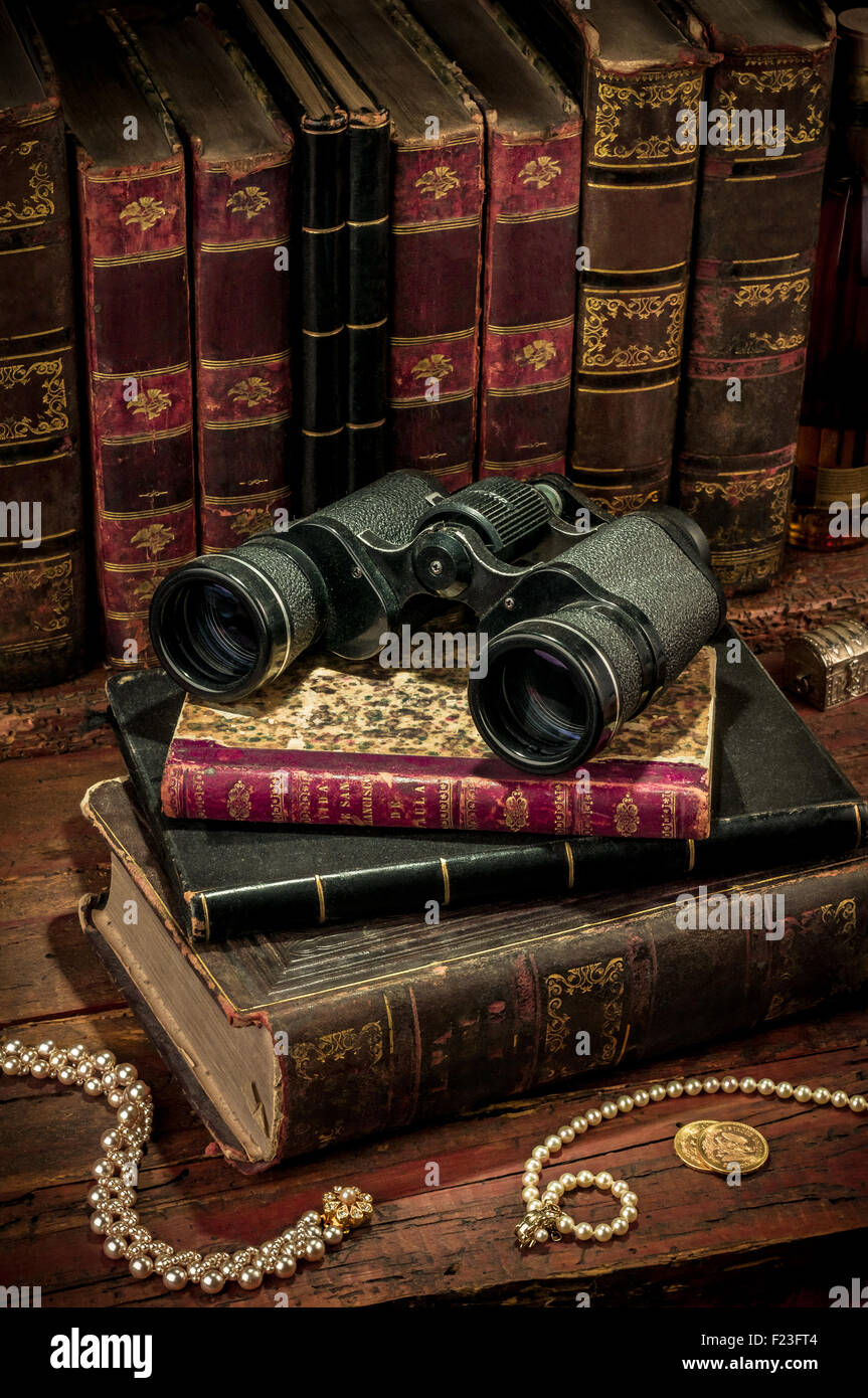 Binoculars and old books over wooden desk Stock Photo