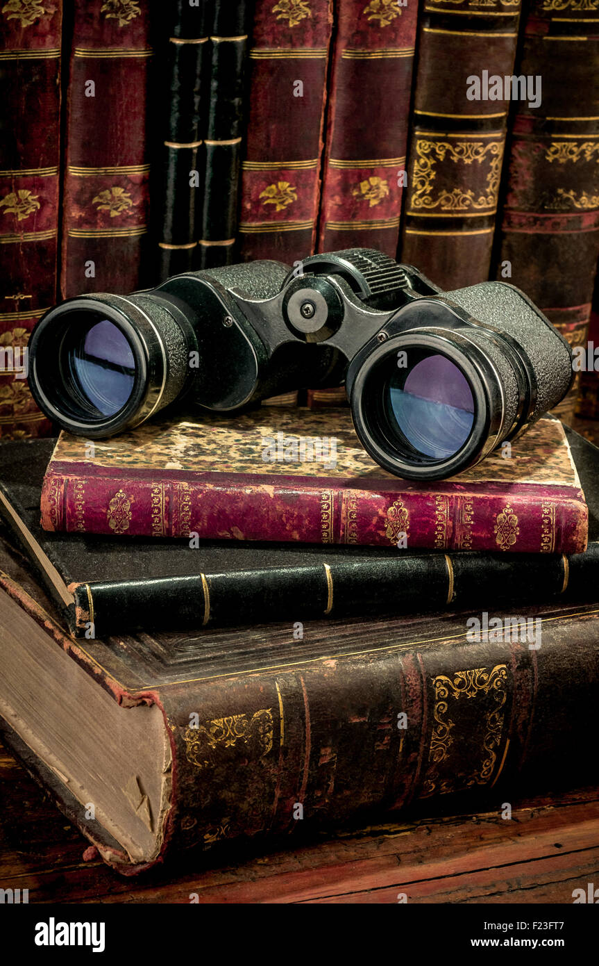 Binoculars and old books over wooden desk Stock Photo