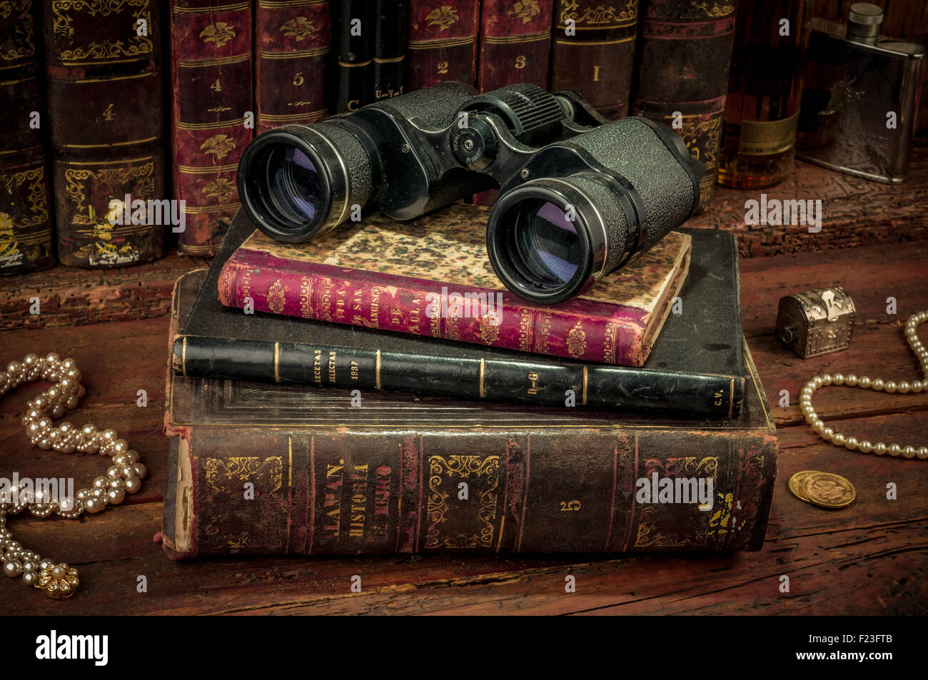 Binoculars and old books over wooden desk Stock Photo