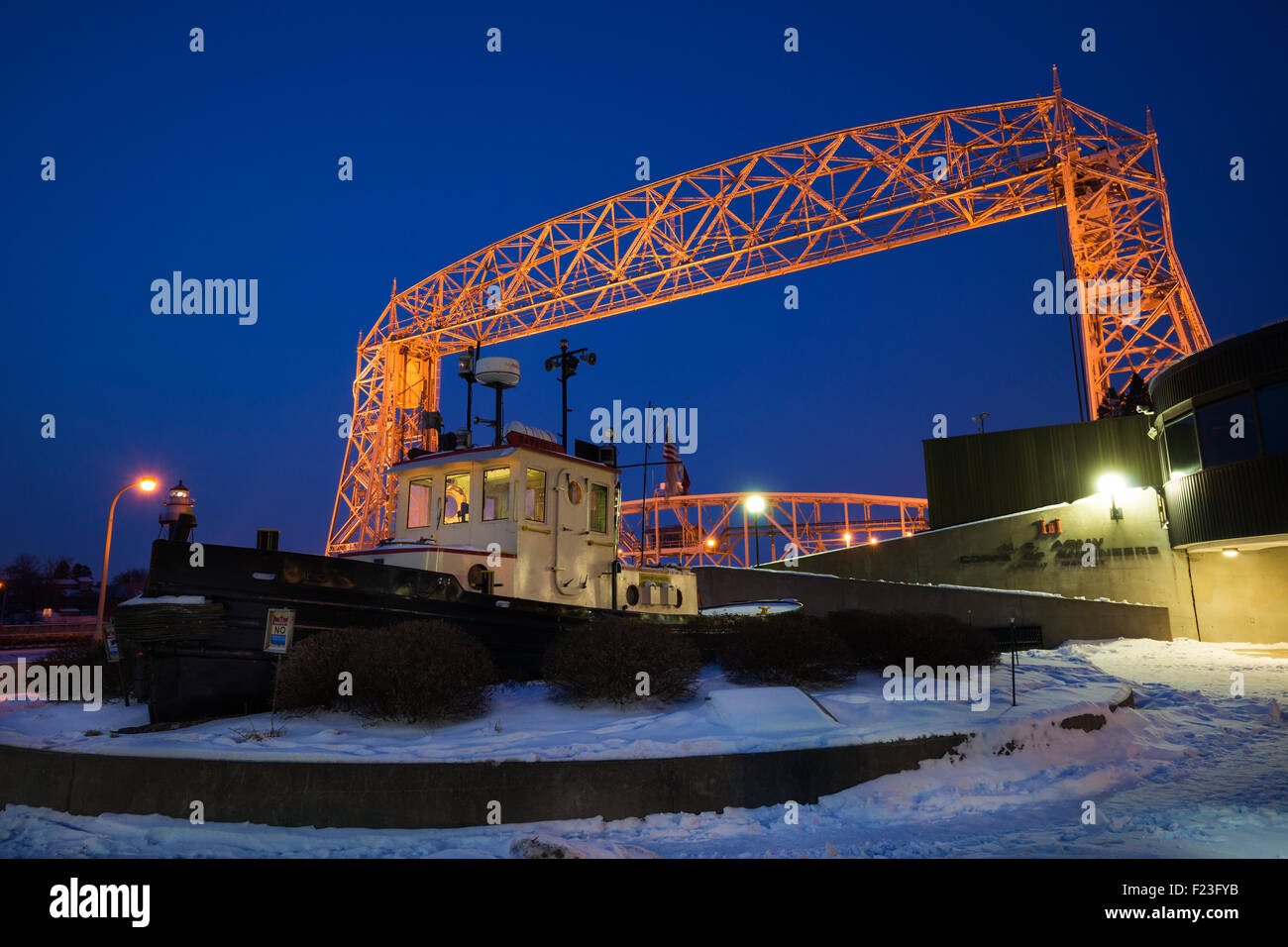Illuminated Aerial bridge over Lake Superior with tug boat in foreground at dawn in winter, Duluth, Minnesota, USA Stock Photo