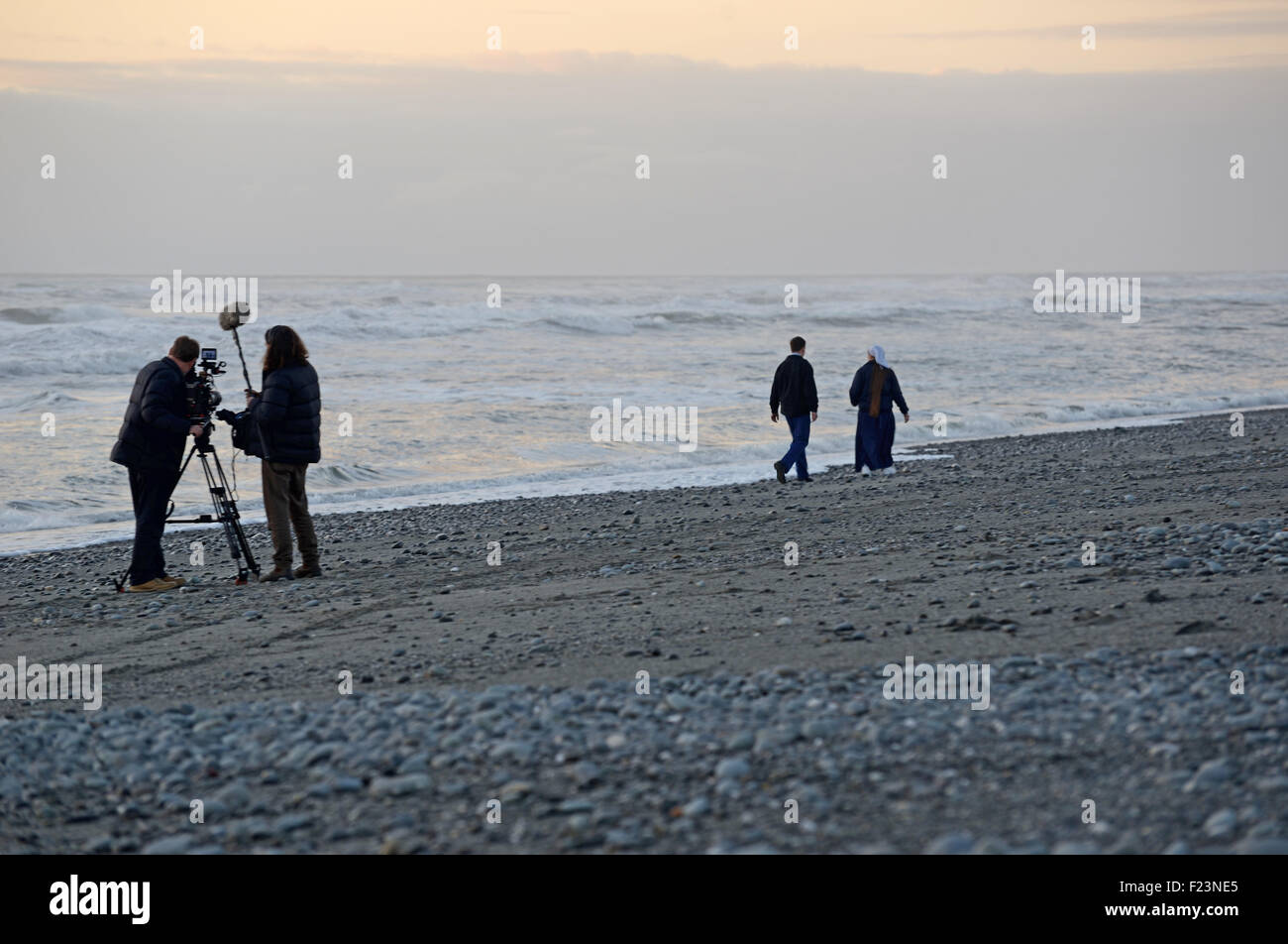 GREYMOUTH, NEW ZEALAND, JULY 30, 2015: A cameraman and sound recordist at work on a New Zealand beach at sunset. Stock Photo