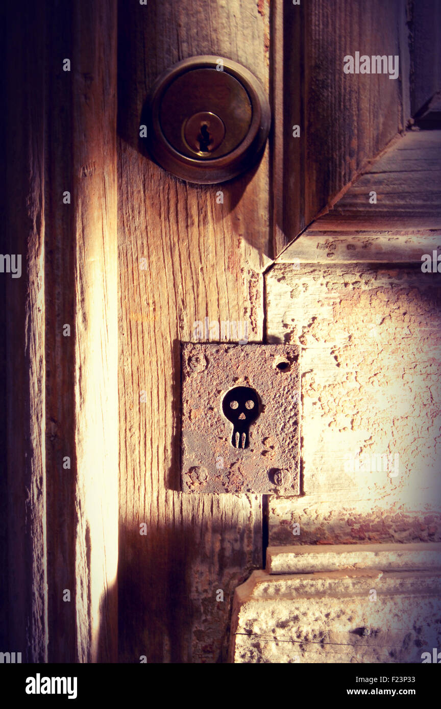 Old wood door with spooky skull keyhole vintage background ideal for Halloween poster. Stock Photo
