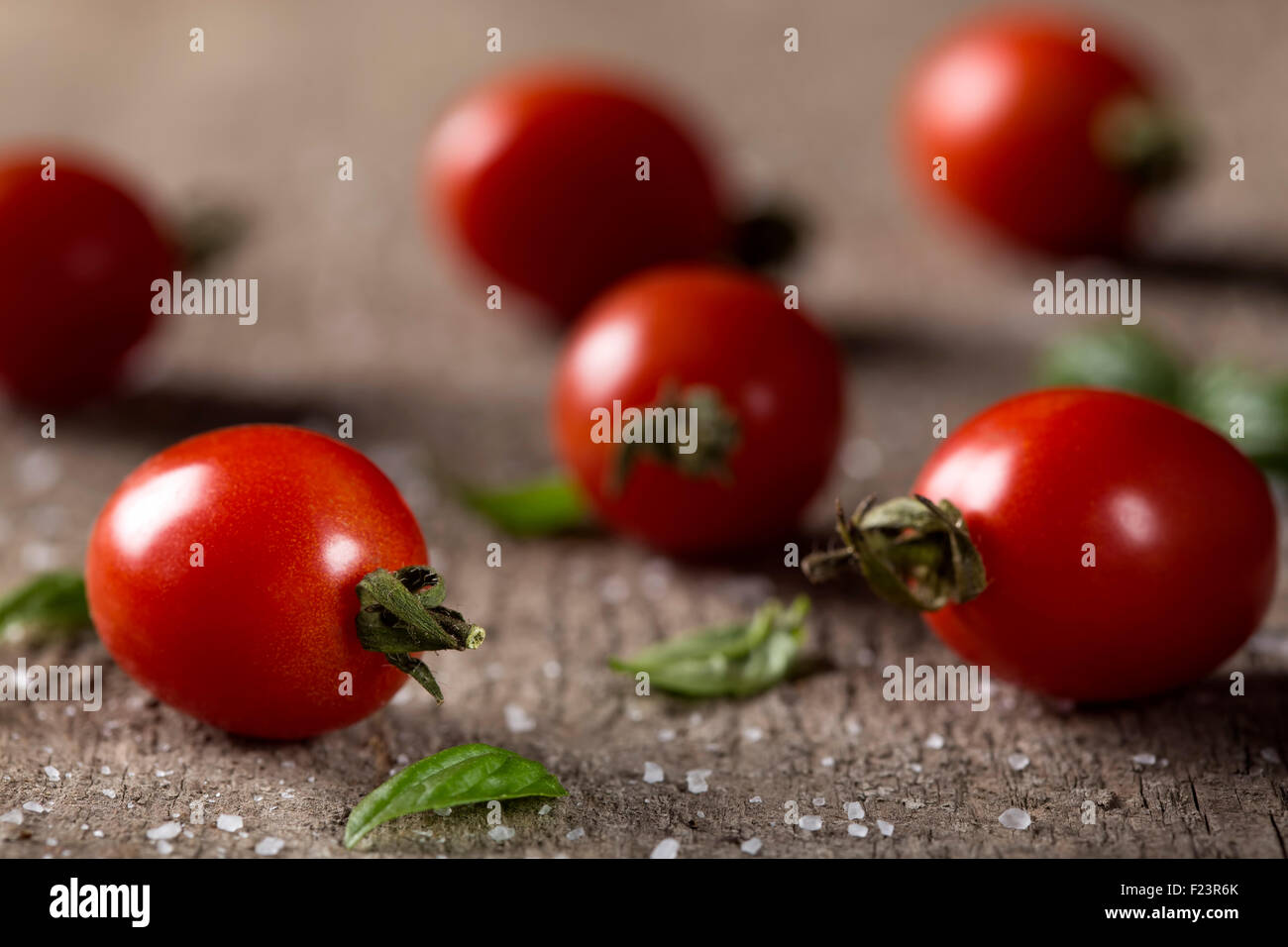 Fresh organic cherry tomatoes with basil and sea salt on rustic wooden ...