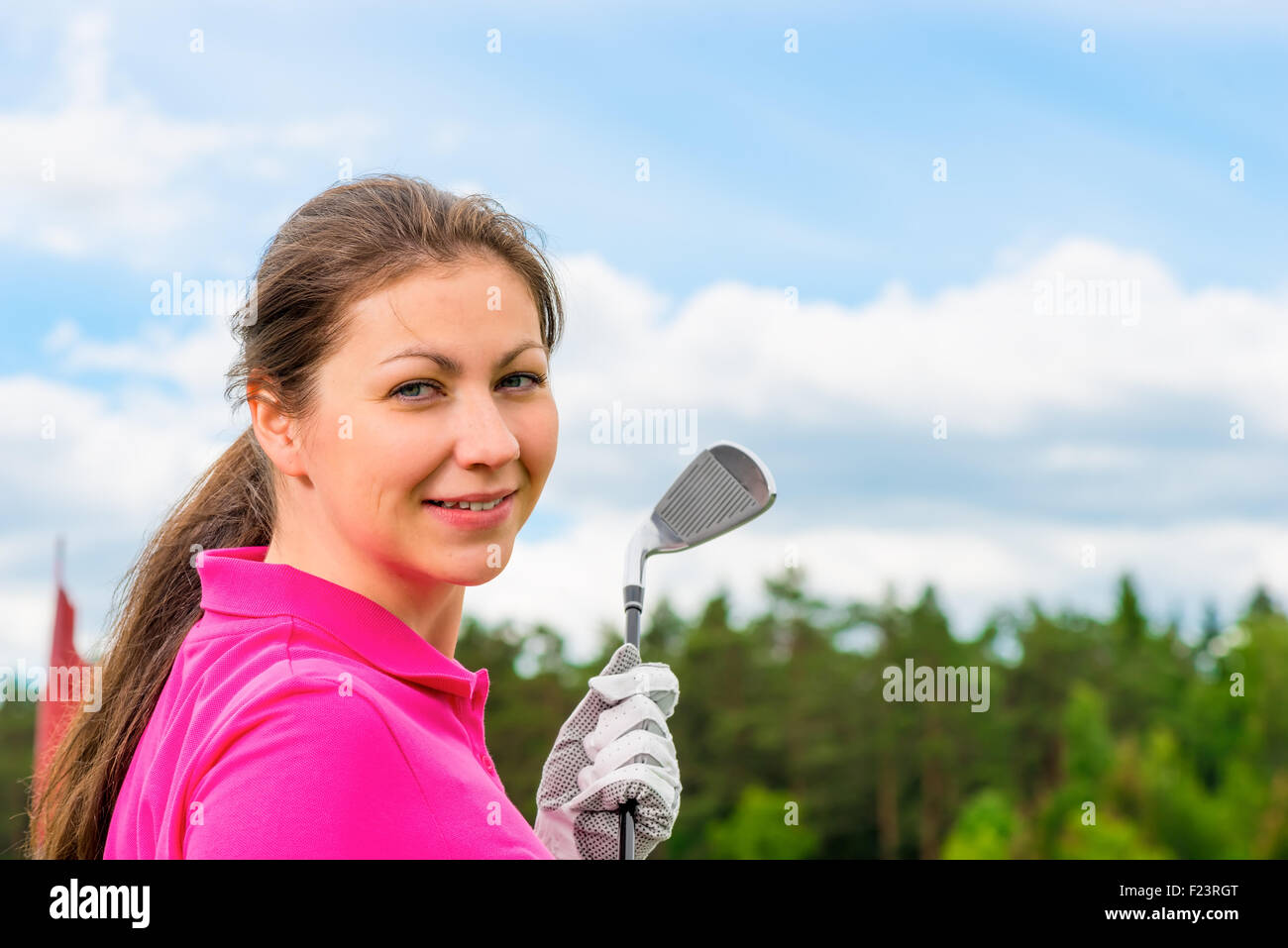 girl in a bright pink T-shirt with a golf club Stock Photo