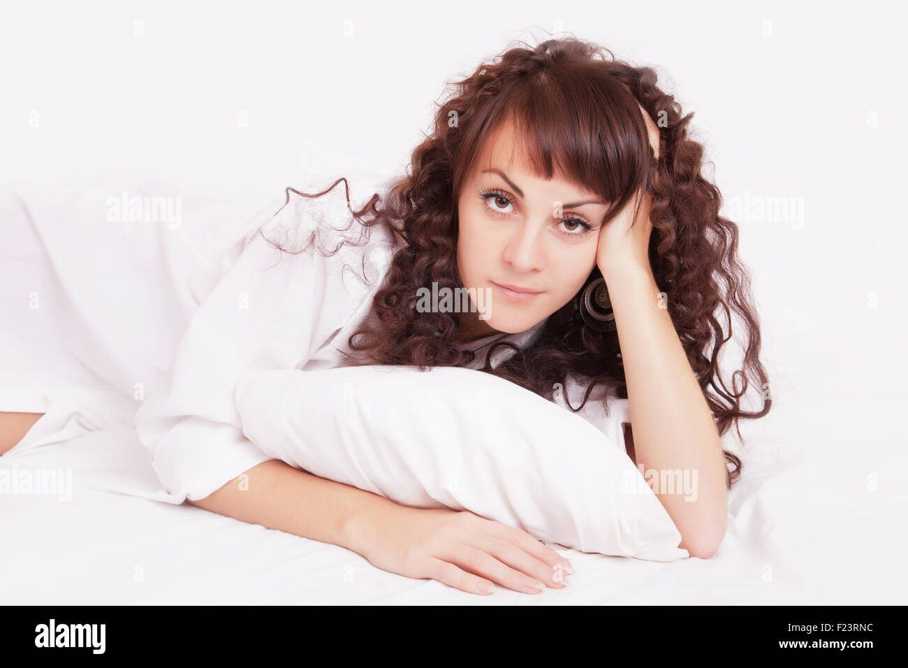 Beautiful young woman in white shirt lying on a bed Stock Photo - Alamy