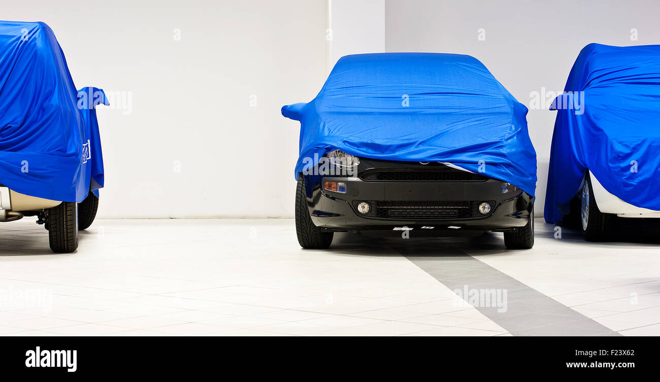 Car covered by a blue sheet in a dealership Stock Photo Alamy