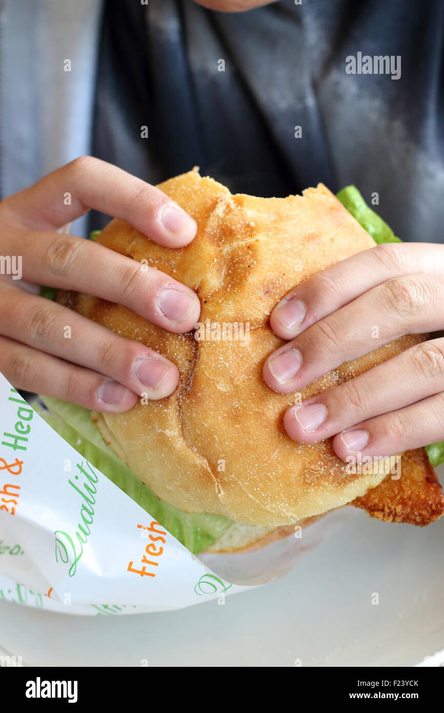 A person holding Chicken Schnitzel burger with  bite missing Stock Photo